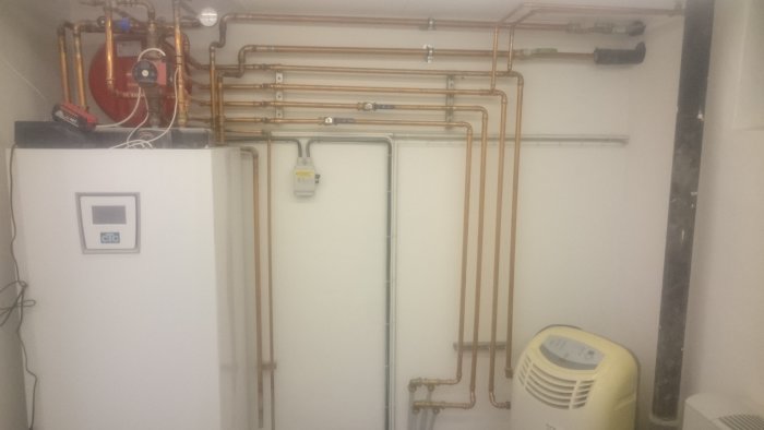 Installation av värmesystem med kopparledningar och värmepump i källare.