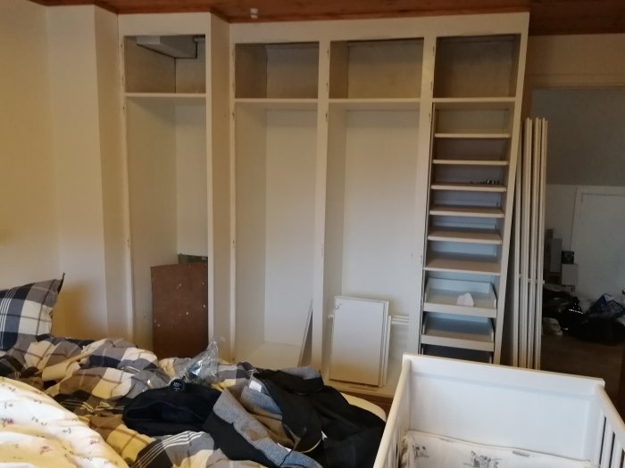 Före renovering: öppna garderober utan dörrar och hyllor, med uppstaplad inredning.