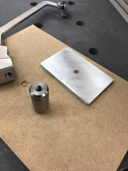 Metallplatta och bult på en arbetsbänk, bulten verkar användas för att spänna plattan.