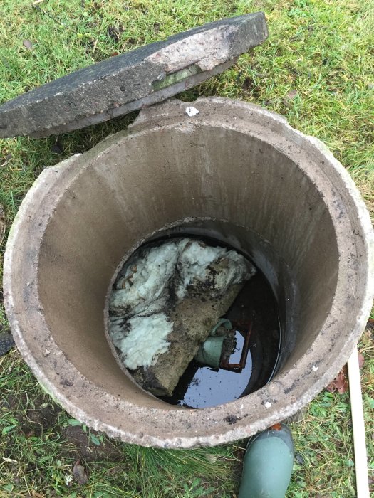 Öppet brunnslock visar en brunnskammare med vatten och isoleringsmaterial.