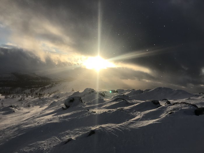 Solnedgång med strålar över snöklädda kullar i Vemdalsskalet, vinterlandskap.