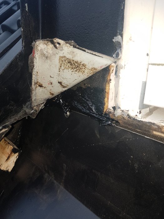 Detaljerad bild av en fönsterkarm med synliga fuktspår och tätklister samt en underlagspapp som är delvis skadad.