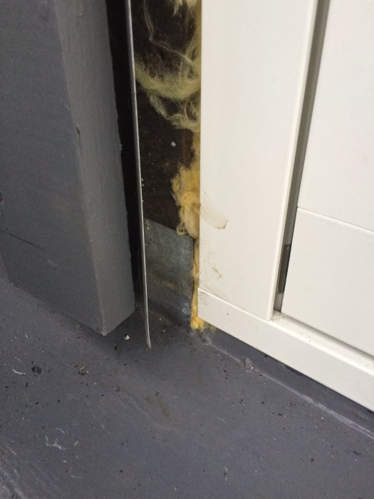 Detaljbild av ett hörn där fönstret möter husväggen, med synlig drevning och en del av fönsterblecket.