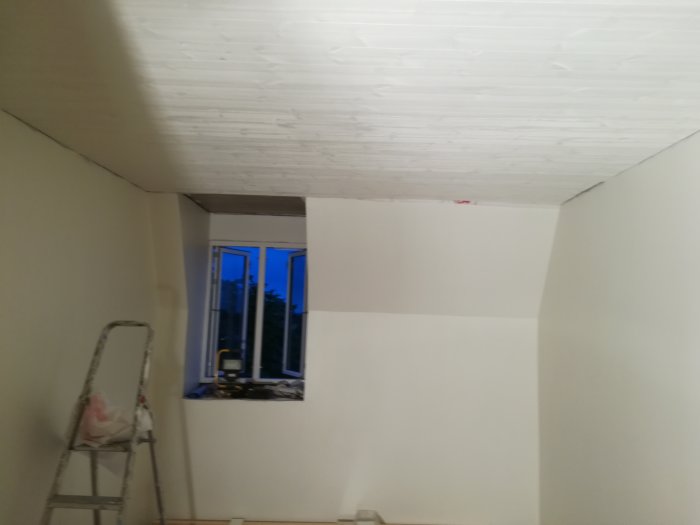 Utrymme under renovering med nytt tak av 140mm bred sågad panel och vy mot nytt dubbelglasfönster, stege till vänster.