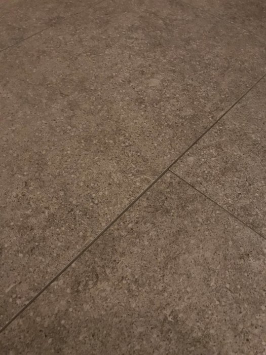 Närbild av beige kakelplattor med synliga men smala fogar på ett golv.