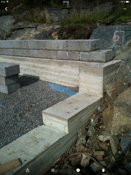 Nybetongklack med dubb intill berg och dräneringsslang underlägg i byggprojekt.
