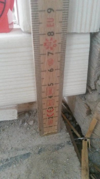 Mätsticka visar 4 cm skillnad i golvhöjd vid en byggarbetsplats.