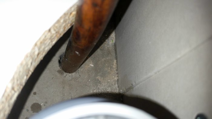 Vattenrör som avviker åt höger inuti ett diskhoskåps utskärning med antydan till sprickor och skador.