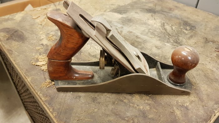 Trähyvel med brutet handtag liggande på en arbetsbänk.