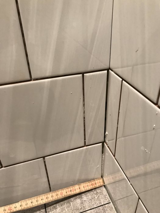 Ojämnt lagda kakelplattor med varierande och breda fogavstånd i ett badrum under renovering.