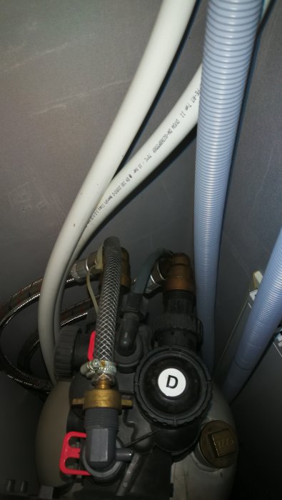 Installation av filterburk med slangar och anslutningar syns ovanför filtertanken.