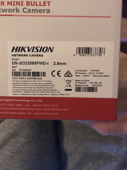 Hand håller låda för Hikvision nätverkskamera med modell och serienummer synliga, klisterlapp märkt.