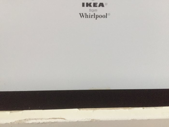 Missfärgat och skadat köksmöblemang med synlig Whirlpool IKEA-logotyp, indikation på vattenskador eller värmeexponering.