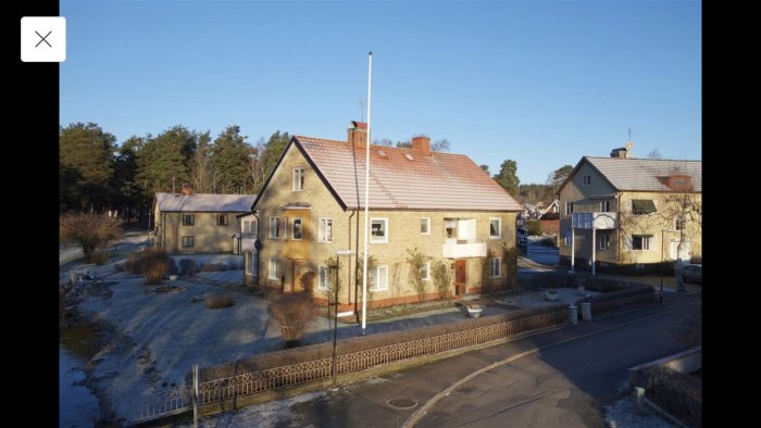 Gammalt tegelhus med åldrat plåttak i vintersol, vill förändra öststatsliknande fasad.