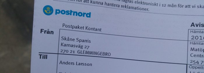 Närbild av ett fraktsedel från Postnord för ett paket adresserat till "Skåne Sparris" med mottagarens namn och adress.