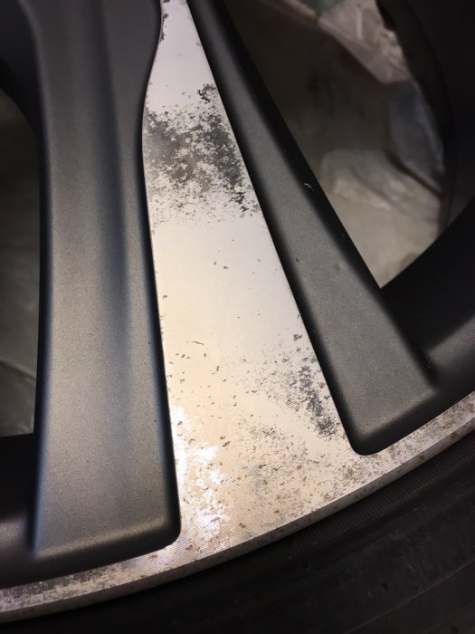 19-tums lättmetallfälg där färgen delvis släppt, visande räfflat underlag och flagnad yta.