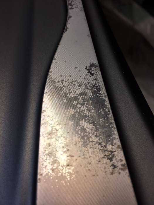 19-tums lättmetallfälg där färgen flagnat av, med synlig räfflad yta under.