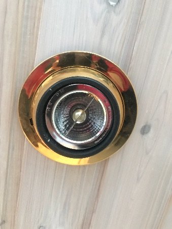 Inbyggd halogenljuskälla i tak med guldig ram på träyta som söker LED-ersättning.