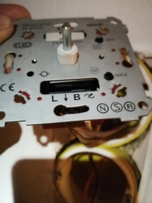 Närbild på en dimmer för rörfläkt med markerade L- och N-uttag och anslutna kablar i en eldosa.