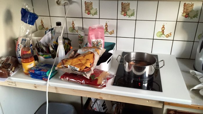 Improviserad köksbänk med ny bänkskiva och induktionshäll, omgiven av diverse livsmedel.