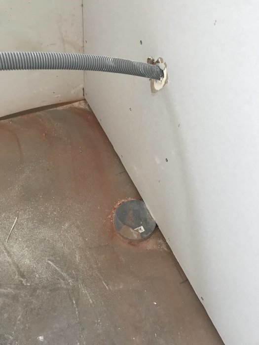 Reglad vägg med OSB och gips, synligt avloppsrör och utskärning för röret i väggen, i ett pågående badrumsprojekt.