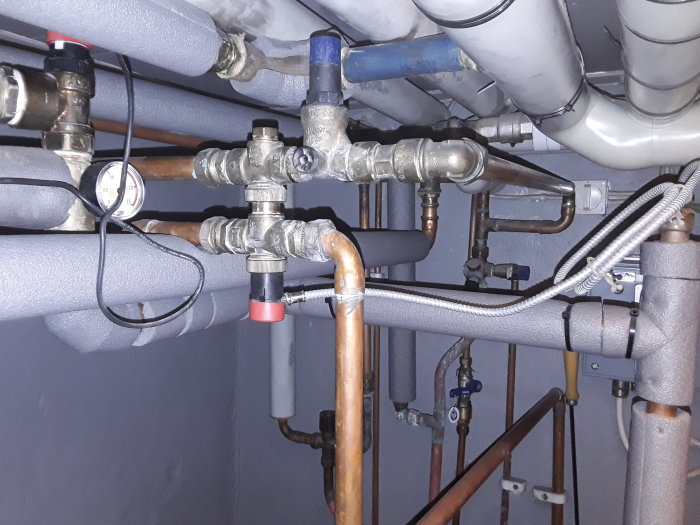 Komplex installation med rör och blå SYR tryckutjämningsventil indikerad för finjustering.