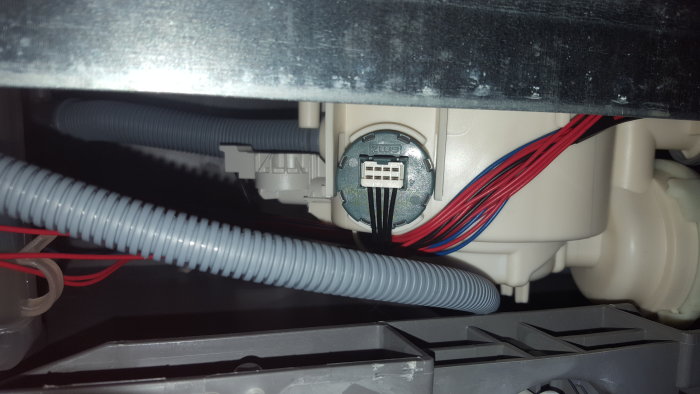Interiör av diskmaskin med synlig tryckvakt och anslutna kablar.
