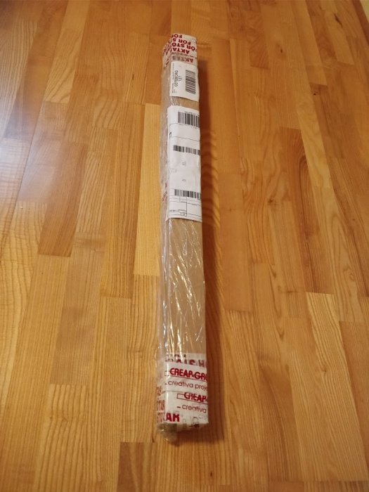 Förpackade aluminiumprofiler från Creap, lindade i hushållspapper och tejp, ligger på ett trägolv.