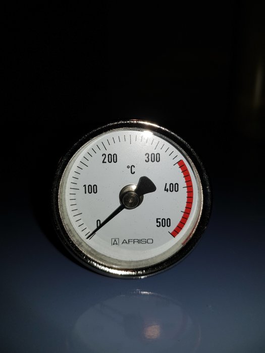 Rökgastermometer från Afriso med visare nära 100°C mot mörk bakgrund.