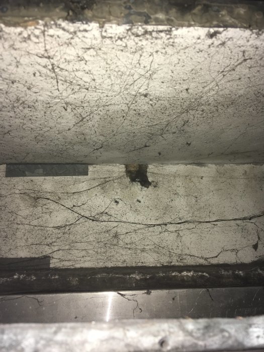 Sliten yta på en ventilationstrumma med texten "381 isol" samt synliga sprickor och möjlig isolering.