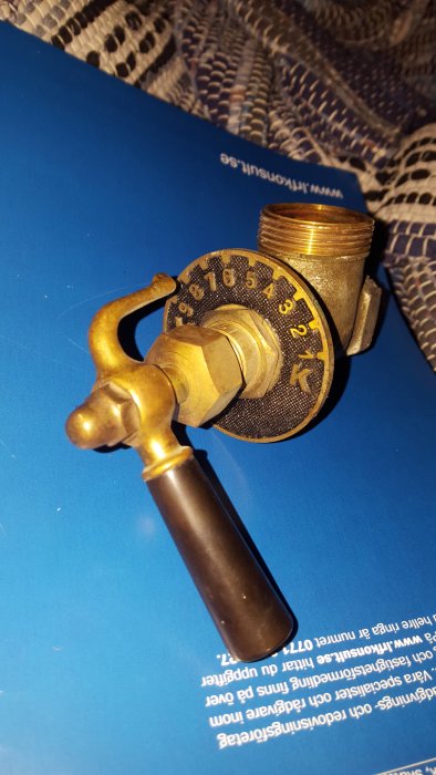 Gammal stil radiatorventil med vred och numrerad skala på en blå bakgrund.