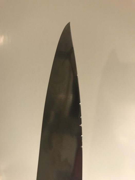 Nyslipad kniv med synliga slipmärken mot en enfärgad bakgrund.