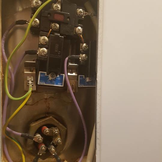 Inuti en varmvattenberedare med synliga elektriska komponenter och termostat inställd på 75 grader.
