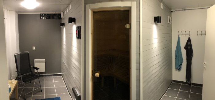 Nybyggt relax-badrum i källare med bastudörr till vänster och handdukshängare till höger.