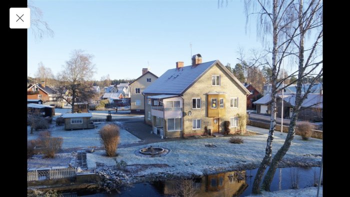 Tvåvåningshus med tre lägenheter, frostigt gräs och spegling i vattnet; planer för ombyggnad.