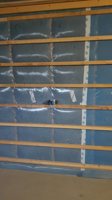 Elektrisk dosa monterad horisontellt mellan träreglar på isolerad vägg med spikläkt.