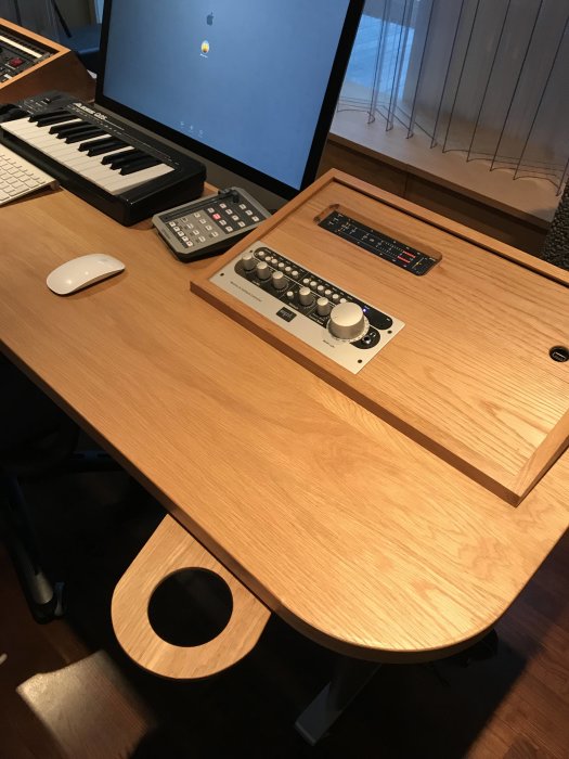 Studiomöbel med ombyggt stativ, audio interface, tangentbord och utfällbar mugghållare med CD-skivor.