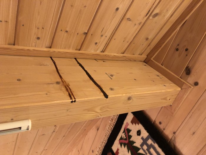 Brunsvarta sega ränder på träpanel i sommarstuga som inte luktar kåda.