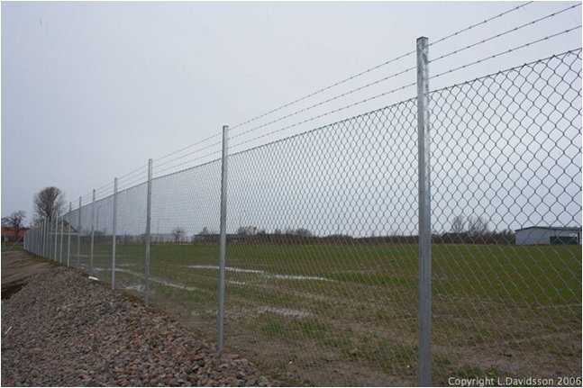 Genomsiktligt industristängsel runt en fastighet, överensstämmande med lokal byggnorm.