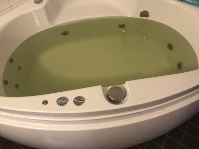 Badkar fyllt med svagt grönt vatten som ska illustrera problemet med misstänkta kopparutfällningar.