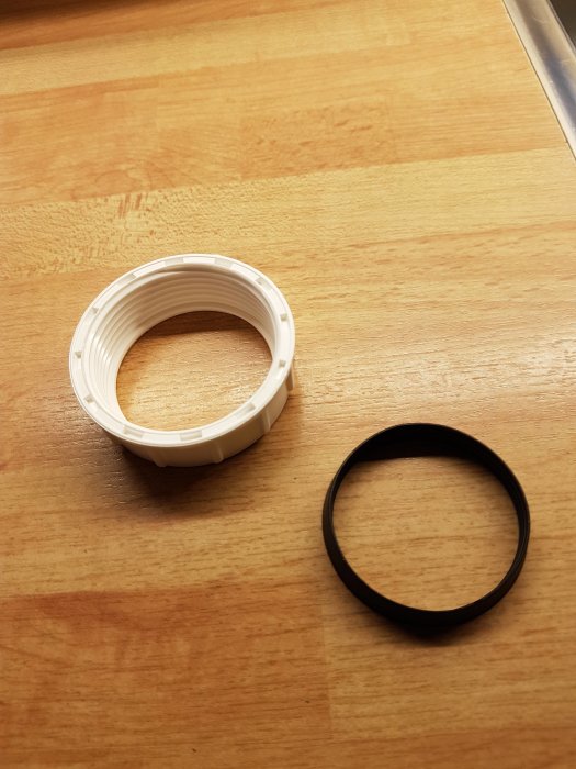 Vit plastmutter och en svart konad packning på ett träbord.