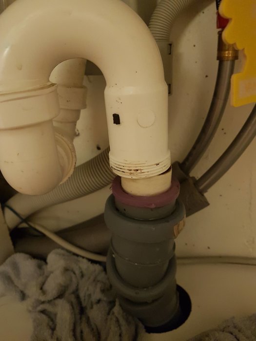 Röranslutning under handfat med en synlig konad packning mellan rördelar.