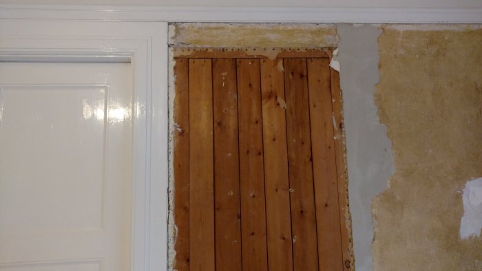 Renoveringsarbete med synliga brädor efter borttaget renoveringsgips bredvid en gammal putsvägg.