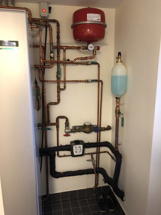 Installation av VVS med kopparledningar, expansionskärl och tryckmätare i ett förråd.