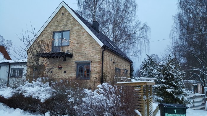 Hus från 1958 med gul tegelfasad, platt tak, och snöbeklädd trädgård, potentiellt område för tillbyggnad.