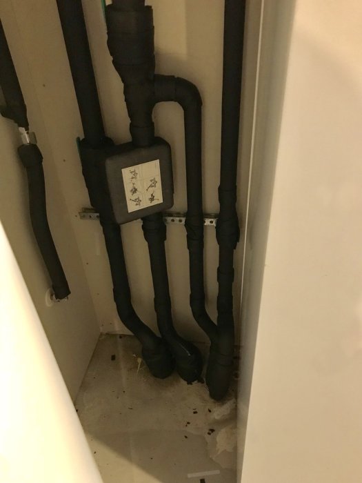 Isolerade VVS-rör och en fuktig betongplatta i ett hörn med synliga vattendroppar.