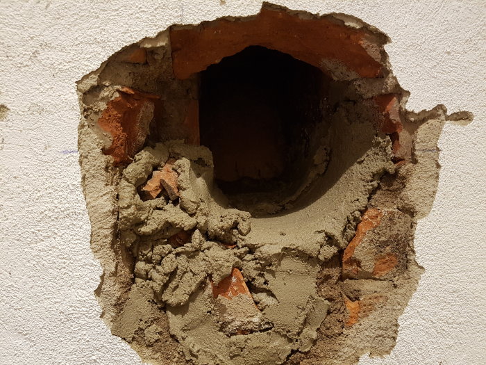 Ett hål i en vägg med synliga tegelstenar och cement, men utan öppning till källaren.