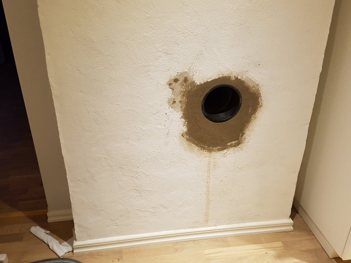 Hål i vägg utan öppning till källaren, visande rörgenomföring och smutsfläckar.