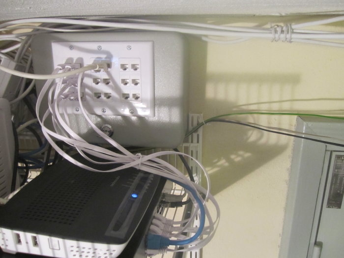 DIY patchpanel installerad i ett nyckelskåp med nätverkskablar och modem.