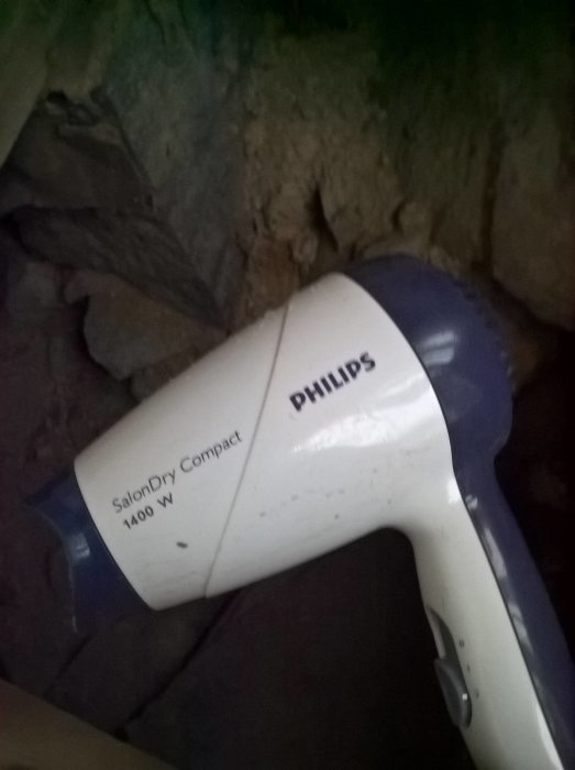 Hårfön från Philips ligger på isolering i en mörk krypgrund.